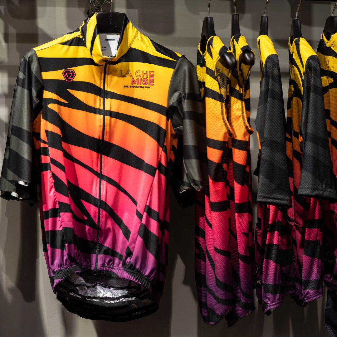 Some yellow gradient jerseys are hanging on a clothes rack.