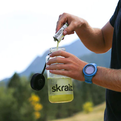 A man is putting a Skratch sports hydration mix into his water bottle.