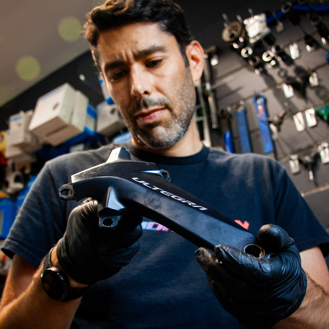 A bike mechanic is inspecting a crank.